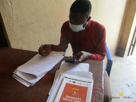 Teacher Bwambabale Gordwin  marking home study work (4)